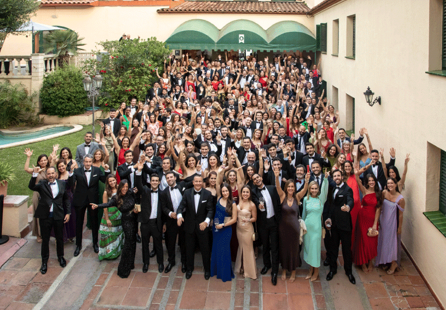 Todos los empleados de Hays España posan en esta fotografía grupal, sonriendo, con las manos alzadas, vestidos de etiqueta. Es un escenario al aire libre, un jardín. Están celebrando la Cena de Gala anual de Hays.